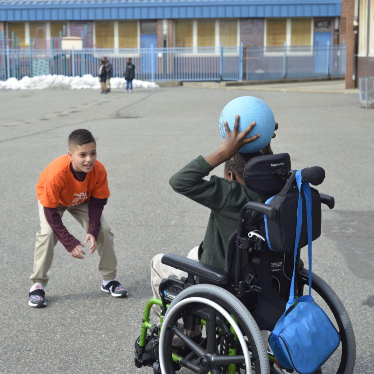 Students in wheelchair throws a ball to student standing